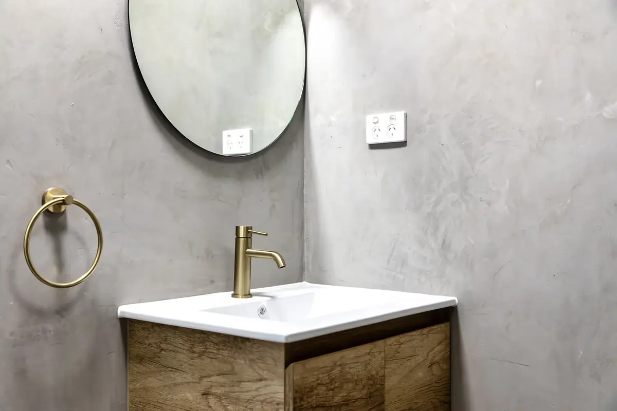 Bathroom vanity with a round mirror and brass tapware