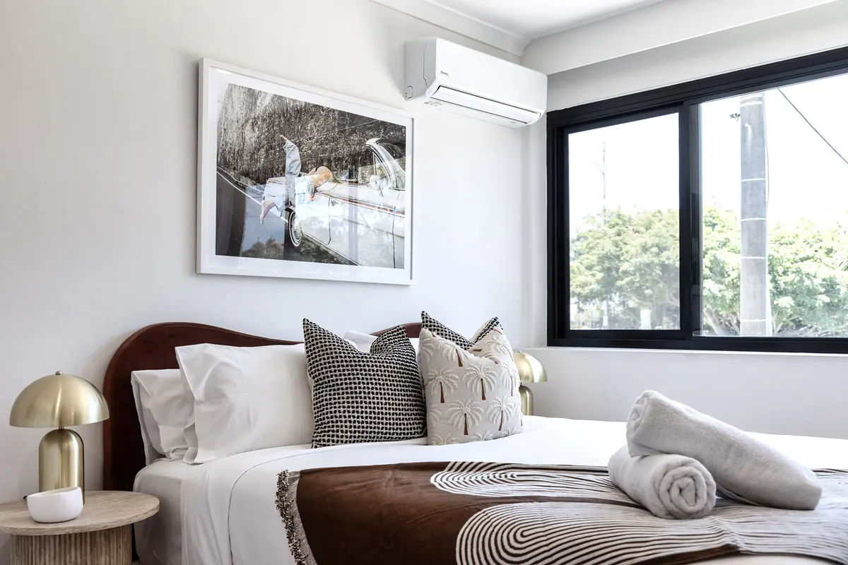 Bed beside a black-framed window with fresh towels