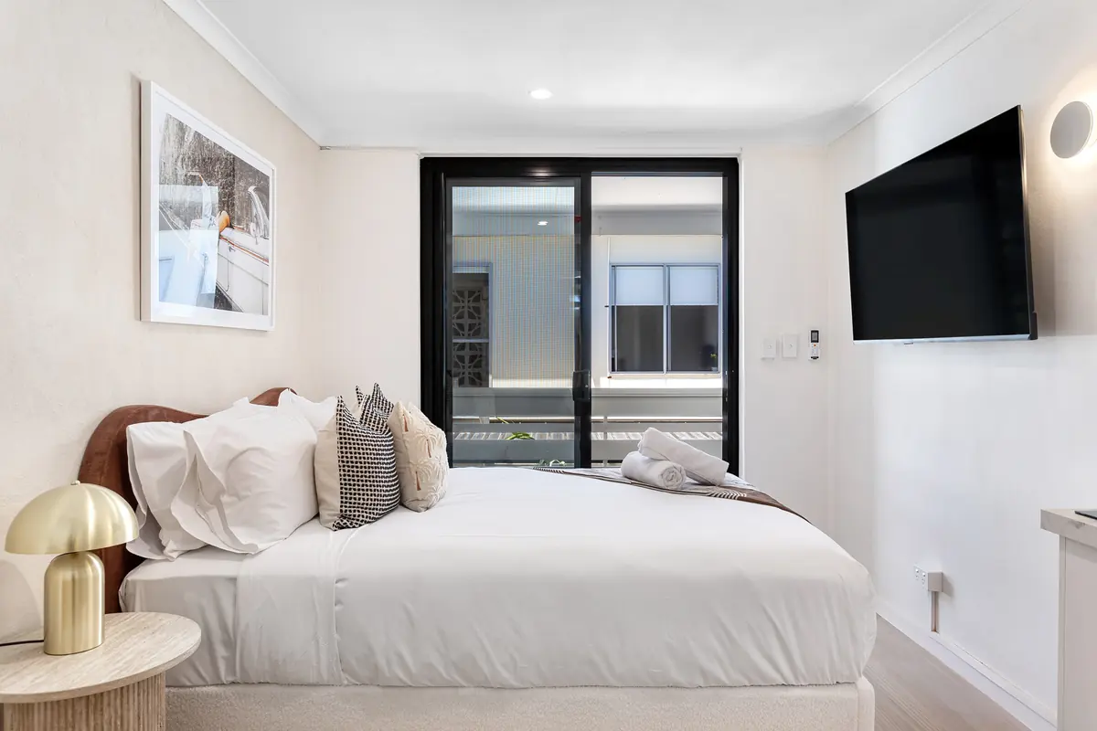 Queen bed and wall-mounted smart TV in a studio at Miami Motel