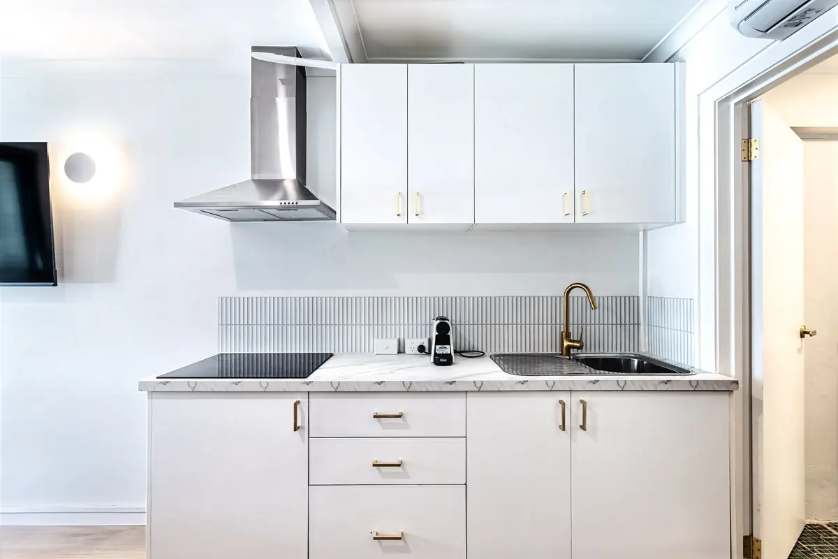 Kitchenette with cooktop, rangehood, sink and brass tapware